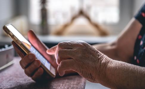 Mãos de uma senhora idosa segurando um celular, close-up
