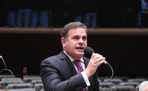 De terno preto, camisa branca, gravata roxa e microfone na mão, João Carlos Barcelar discursa na Câmara dos Deputados