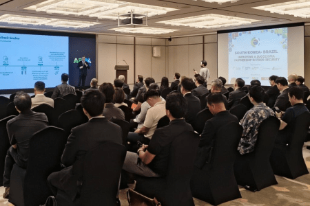 Público acompanha seminário em auditório, com apresentações projetadas em duas telas sobre a parceria entre Coreia do Sul e Brasil na segurança alimentar.