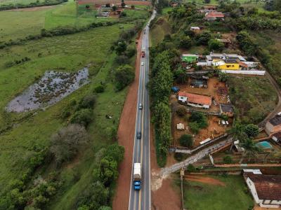 Máquinas e equipes de obras trabalhando na melhoria e nivelamento da faixa de domínio às margens de uma rodovia.