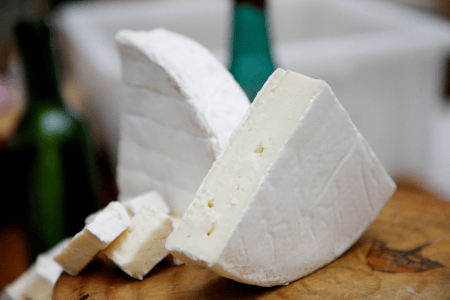 Queijo artesanal de formato arredondado, com casca e textura características de um produto maturado, apresentado para consumo.