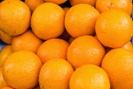Laranjas de casca alaranjada agrupadas em destaque.