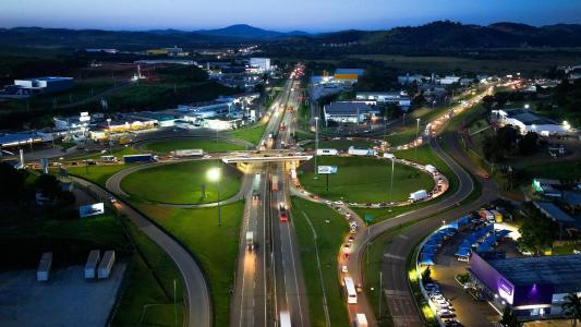 Tráfego de veículos em trecho da rodovia Fernão Dias sob sinalização sob chuva.