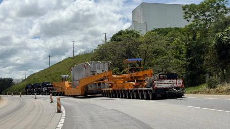 Conjunto transportador de grande porte transportando carga superdimensionada em rodovia.