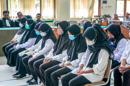 Mulheres acusadas de maus-tratos reagem enquanto acompanham os procedimentos durante o julgamento por abuso e negligência infantil