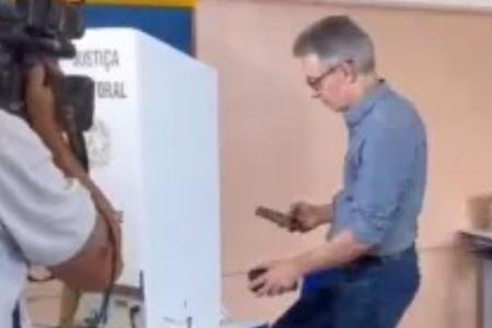 Romeu Zema utiliza celular em local de votação