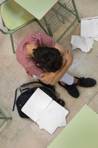 Aluno vítima de bullying sentado no chão triste