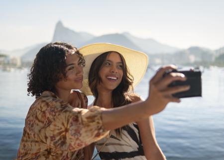 Duas mulheres sorriem enquanto tiram foto em viagem internacional.