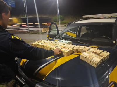 Mala com notas de dinheiro em espécie apreendida pela Polícia Rodoviária Federal no porta-malas do veículo.