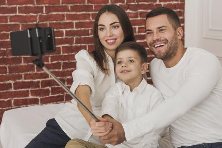 Família composta por mãe, pai e criança tirando selfie