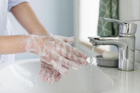 Pessoa lavando as mãos com água e sabão