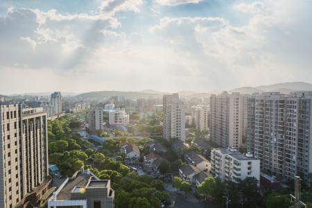 Vista de cima de um bairro residencial, com prédios nas extremidades e casas no centro com árvores dispostas no centro da foto