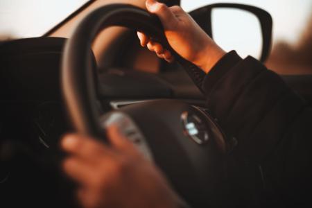 Imagem mostra duas mãos segurando um volante.